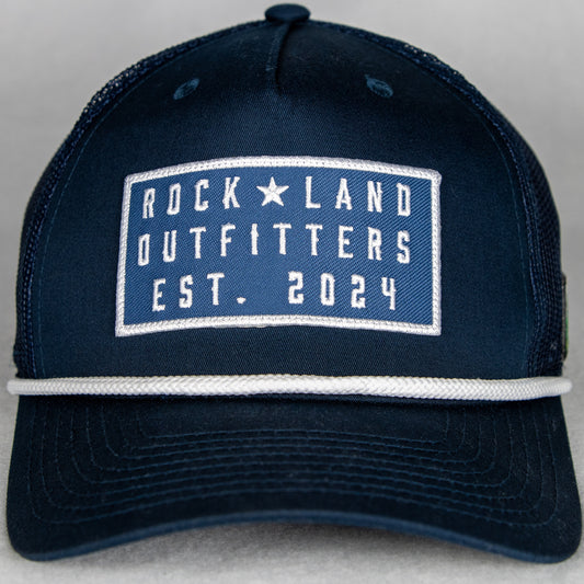 Rock Land Outfitters Blue Logo Patch On A Navy Hat With A White Rope