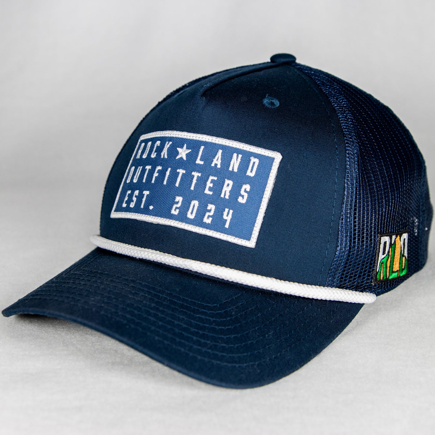 Rock Land Outfitters Blue Logo Patch On A Navy Hat With A White Rope